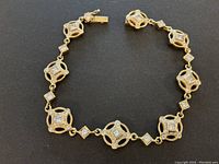 Full-length top view of yellow gold bracelet with alternating openwork square links and diamond connectors