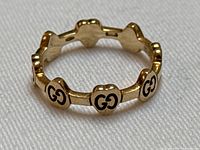 Front view of ring showing repeating heart-shaped links with black enamel double G logos.