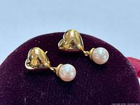 Front view of paired earrings displayed on purple velvet