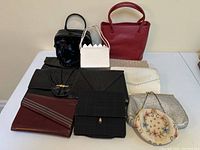 Overview of nine handbags and clutches arranged on table