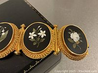 Close-up of three central oval panels showing white floral pietra dura inlay on black marble