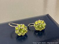 Front view of pair of white gold peridot cluster earrings showing oval and round stones