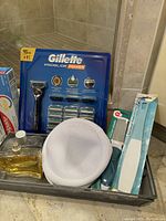 Photo of Gillette Proglide Power Razor in packaging, mesh toiletries bag, and assorted personal care items in a basket.