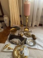 Full view of assortment laid on white cloth, including candlestick with candle, shell salt and pepper shakers, candle snuffer, fish-shaped napkin holder, pierced silver dish, sunflower key holder.