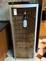 Full front view of Haier wine cooler showing smoked glass door and metal racks inside.