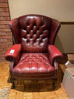 Front view of red tufted wingback chair on parquet floor