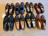 6 pairs of men's leather shoes in brown and black with wooden shoe trees inside. Assorted styles including tassels, horsebit, woven leather, in good condition.