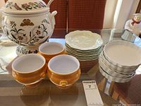 Complete set of soup tureen, ladle, side plates, tart plates, and mini bowls arranged on table.