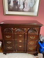 Front view of the Thomasville 4 drawer dresser showing carved fan-shaped motifs and brass handles on a polished wooden finish.