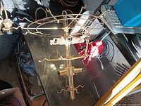 Brass bar light fixture with multiple light sockets and pull chains on a metal surface.