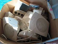 Box containing multiple electronic devices including two white air purifiers, a beige sleep machine, cordless phone base and handset, and small shower radio.