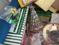 Various decorative and household items including boxed porcelain candle holder, glass Christmas tree ornament, and other small household items.