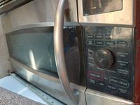 Close-up of control panel and door handle of stainless steel over stove convection microwave oven.