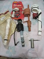 Plumbing parts including various toilet tank fill valves and plugs, some in original packaging