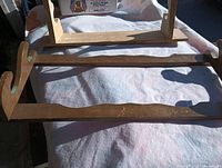 Two wooden firearm racks laid on white cloth, showing hanging slots and brown finish