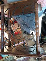 Top view of wooden wine rack showing metal circular bottle holders and wooden frame with turned columns.