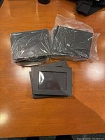 Stack of magnetic makeup palettes sealed in plastic packaging and some without plastic, placed on wooden surface.