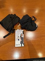 Three black smocks laid on table with packaging showing 'Stylish Adjustable Smock' by Bois d'Arc