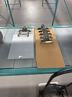 Photo showing a metal clip board, three particle board clip boards, and one plastic clip board