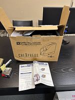 Digital Check CheXpress box on table with instruction manual and device partially visible inside box
