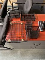 View of all wire basket and mesh desk organizers on a wooden desk, showing shapes and sizes