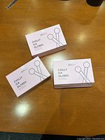 Three pastel pink boxes of Skin Gear Chilly Ice Globes laid out on a wooden surface.