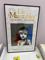 Front view of signed Les Miserables musical poster in black frame, showing signatures and title design.