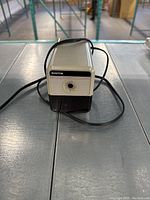 Front view of the Boston branded electric pencil sharpener with power cord on a metal shelf.