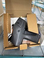 Top view of black Monarch Marking hand-held pricing tool inside open cardboard box.