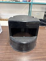 Front view of a round black plastic step stool showing ribbed top surface and open underside