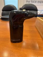 Black handheld Temptu Air airbrush tool upright on table