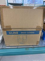 Closed brown cardboard box labeled "Uline Shoe Covers" on the side.