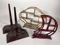 Two pairs of wooden display stands: one pair of dark vertical rectangular base stands, and two ornamental shelf style stands, one in faded light brown and the other crescent-shaped dark reddish-brown.