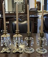 First photo showing two pairs of brass girandole candleholders with beige taper candles in place, highlighting overall appearance and varying heights of approximately 3.5 and 8.5 inches.