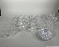 Full lot showing all crystal glasses and dessert plates arranged by size and type on white background