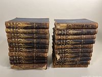 Two stacks showing all 20 volumes of The Book of Knowledge Children’s Encyclopedia from 1911-1912 with worn covers and bindings