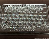 Tray with clear faceted fire polished glass balls, teardrop prisms, and octagonal jewel chain crystal pieces arranged closely together showing prism reflections.