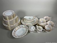 Overview of entire dish set including stack of plates, cups, saucers, serving pieces