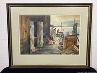 Framed signed Alan Franks watercolour painting showing dockside scene with barrels, seagulls, and a man working at the end of a dock overlooking water. Frame and cream double mat visible.