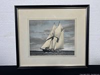 Framed nautical photograph of Bluenose sailboat under full sail on water, showing entire frame and matting.