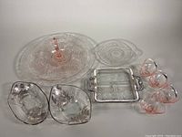 All items laid out showing set contents including large pink depression glass plate, divided glass dish with silver plated handles, four small pink baskets, two clear floral overlay dishes, and small clear round dish.