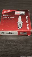Original box of 4 Champion Copper Plus spark plugs showing model number 322 RN11YC4 and product branding.