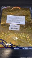 Photo of gold holographic gift bag with yellow handles still in packaging.