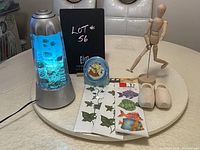 Children's lamp with fish design lit, Winnie the Pooh clock, wooden shoes, mannequin, and room decals displayed on a round table.