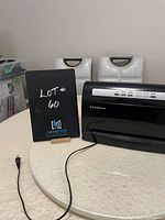 Black FoodSaver V3460 food vacuum sealer on white table with visible white paint on side and power cord extended.