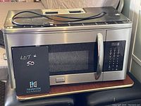 Frigidaire large stainless steel microwave with digital panel and handle, top view shows power cord and some surface scratches.