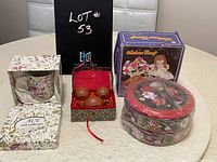 Wide view showing all three gift sets on white table with white tiled background: floral cup in box, mini tea set in decorative red-box, and Sakura candy dishes in plastic wrapping.