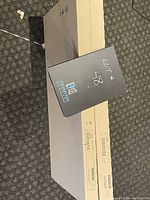 Photo showing one unopened IKEA Effektiv desk box lying flat on a carpeted floor with a black label indicating lot number 48.