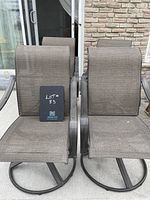 Front view of two metal and mesh fabric swivel lawn chairs, showing seating area and chair backs.