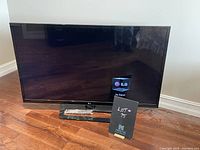 Photo showing full front view of LG flat screen TV with 'No Signal' on screen and built-in stand on a wood floor.
